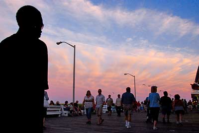 Photo: Man silouetted against a brilliant sky walking with purpose towards a crowd of people