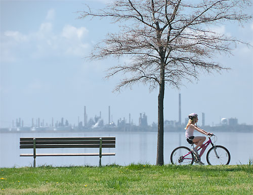 Girl bicycling near oil reflnery