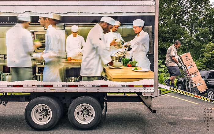 Photo by Danny N. Schweers of a man unloading four boxes of fresh shell eggs from a US Foods truck with a photo of six busy chefs on its side.