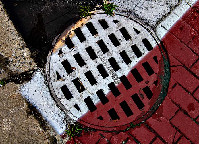Photo of painted steel water drain cover at crosswalk in Ludlow, Vermont by Danny N. Schweers