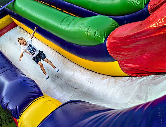 Photo of a mid-air boy on inflatable slide, Arden Fair, Arden, Delaware by Danny N. Schweers, 2019.